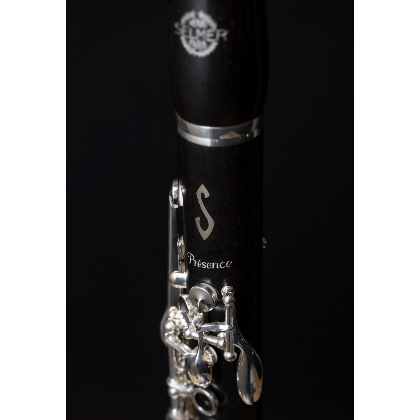 closeup of Presence logo and inlaid Selmer S insignia on upper joint against black background