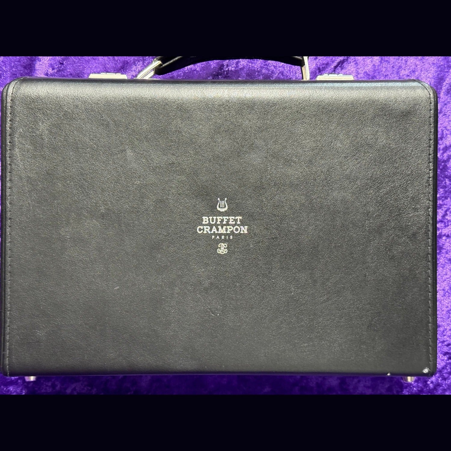 Buffet Crampon attache case, closed, featuring logo on top, on a purple background