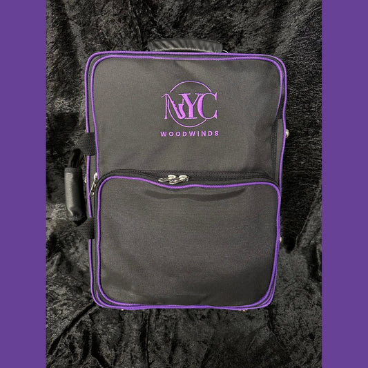 black NYC Woodwinds branded Marcus Bonna double clarinet case with logo and piping in purple, the rest of the case is black, and it sits on black velvet