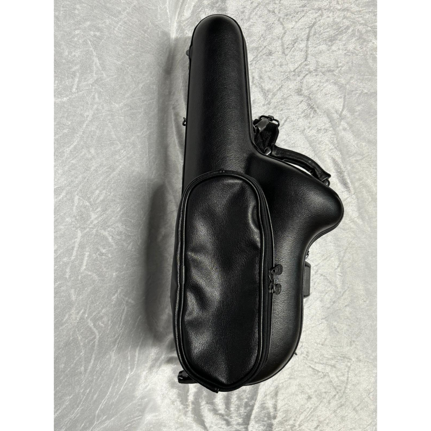 black leather case, closed, showing accessory pouch on the outside, against white velvet background