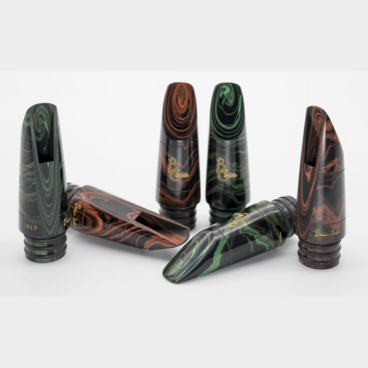 A selection of Corbin Signature Bb clarinet mouthpieces in red and green marbled ebonite, arranged on a white background