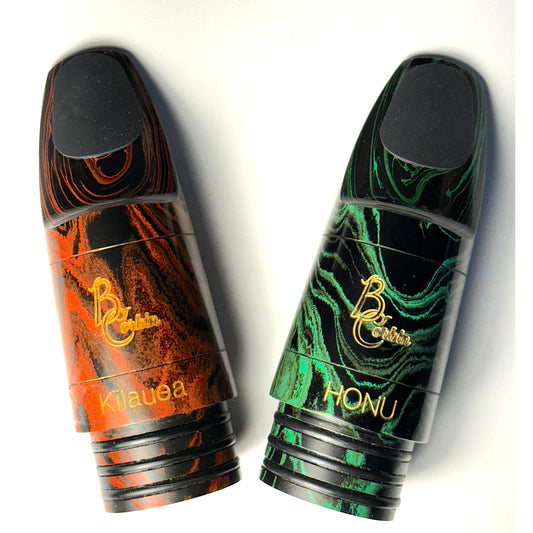 Two Corbin marbled rubber mouthpieces, Honu (green and black) and Kilauea (red and black), against white background