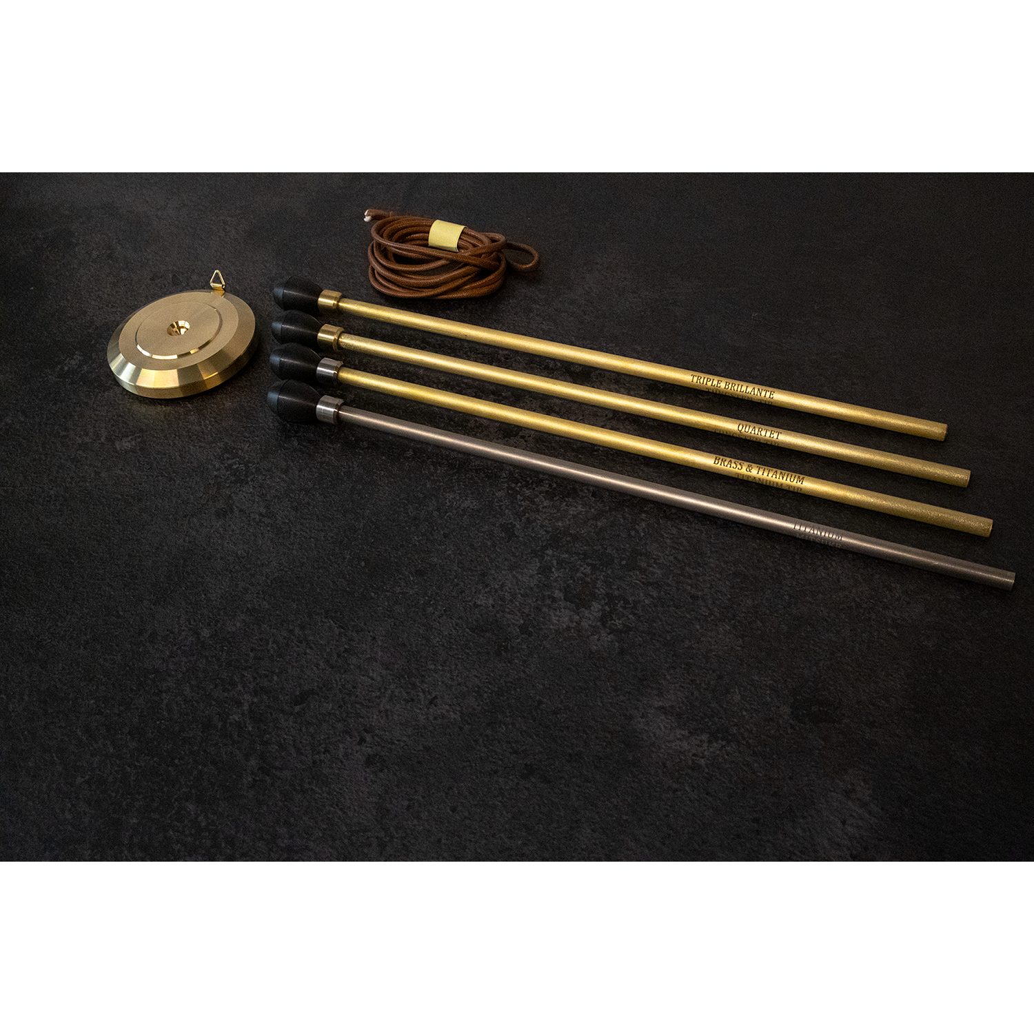 Mitsuke Endpins - pin models with rubber tip caps lined up next to stopper and attachment cord (top to bottom: triple brilliante, quartet brass & titanium with titanium tip, titanium)