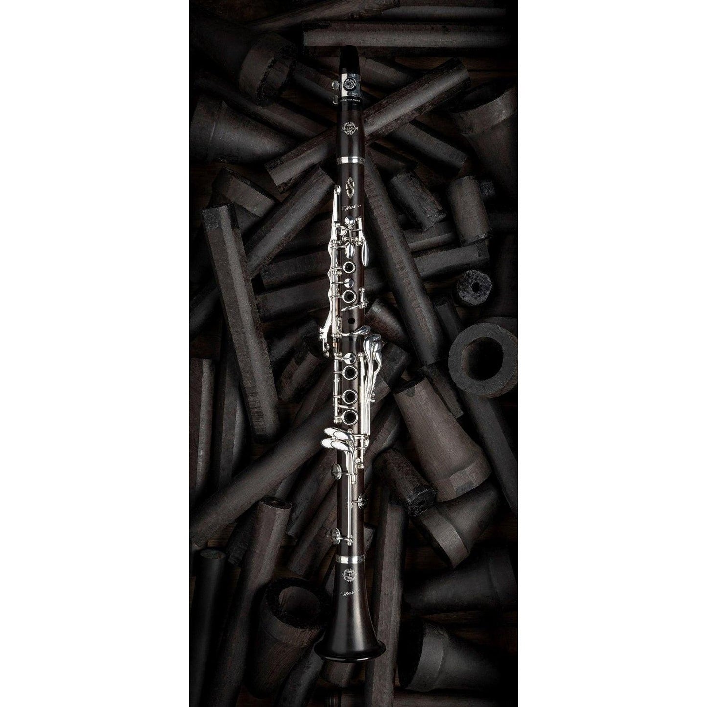 fully assembled Muse clarinet on background of grenadilla wood billets in various stages of finishing