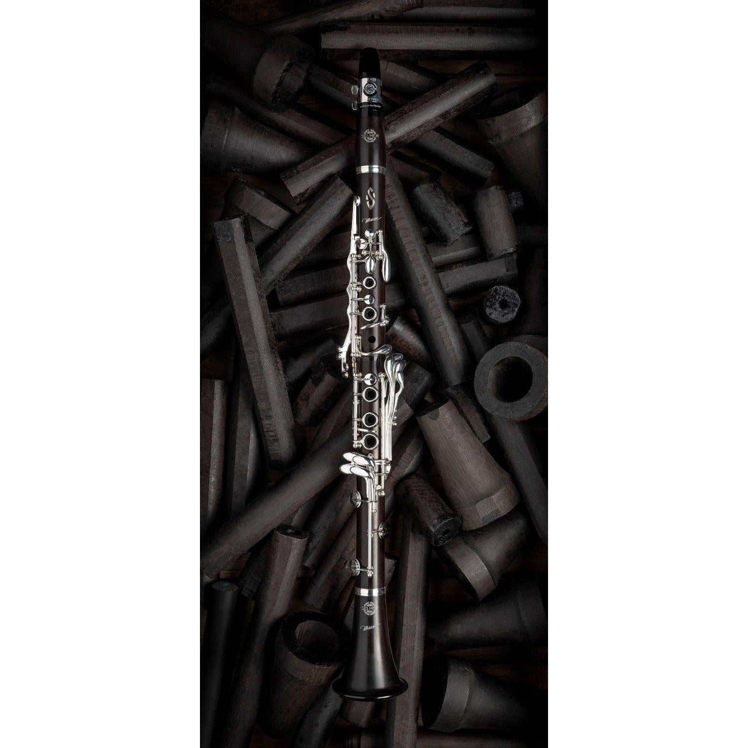 fully assembled Muse clarinet on background of grenadilla wood billets in various stages of finishing