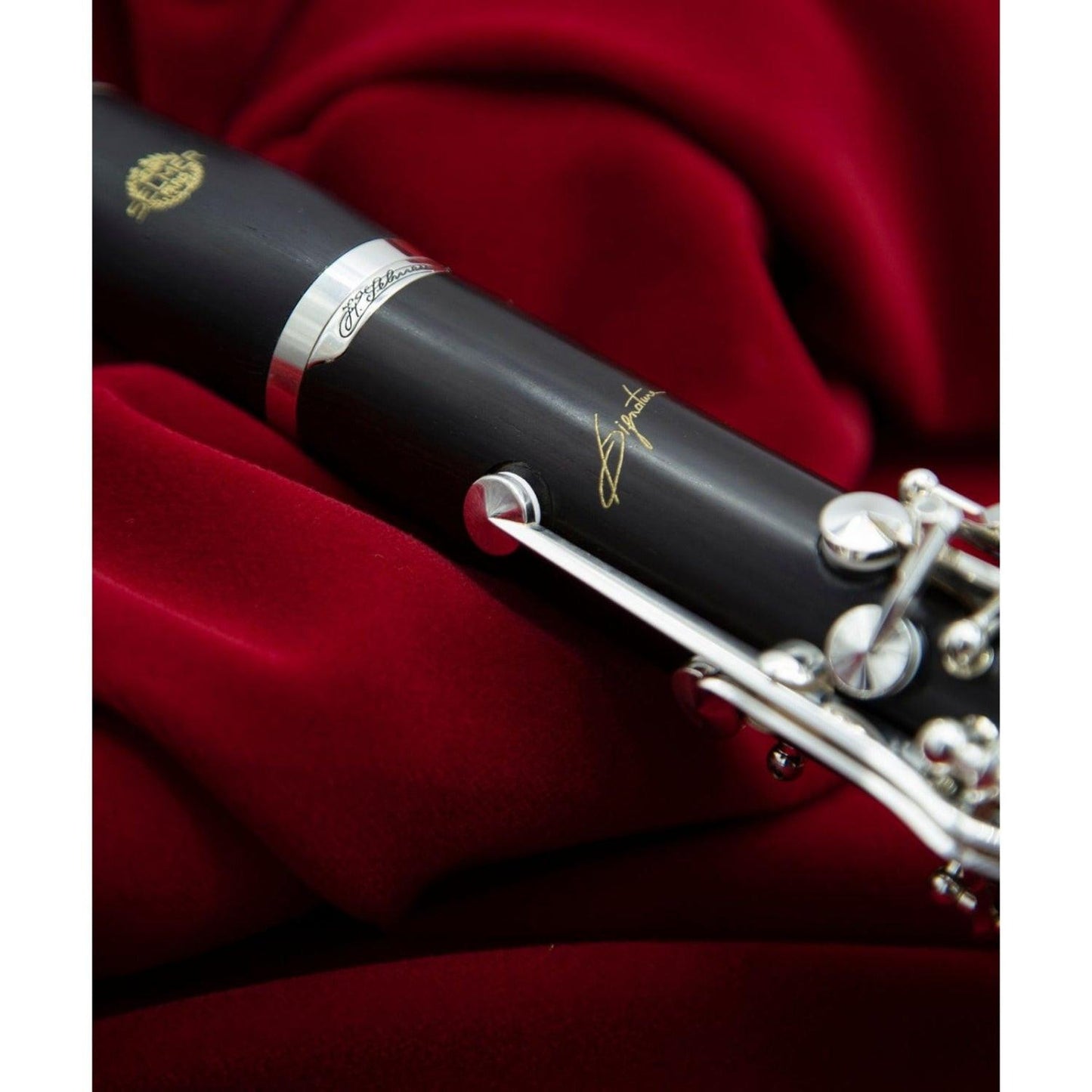 closeup of Signature logo and upper joint silver Signature plate against red fabric background