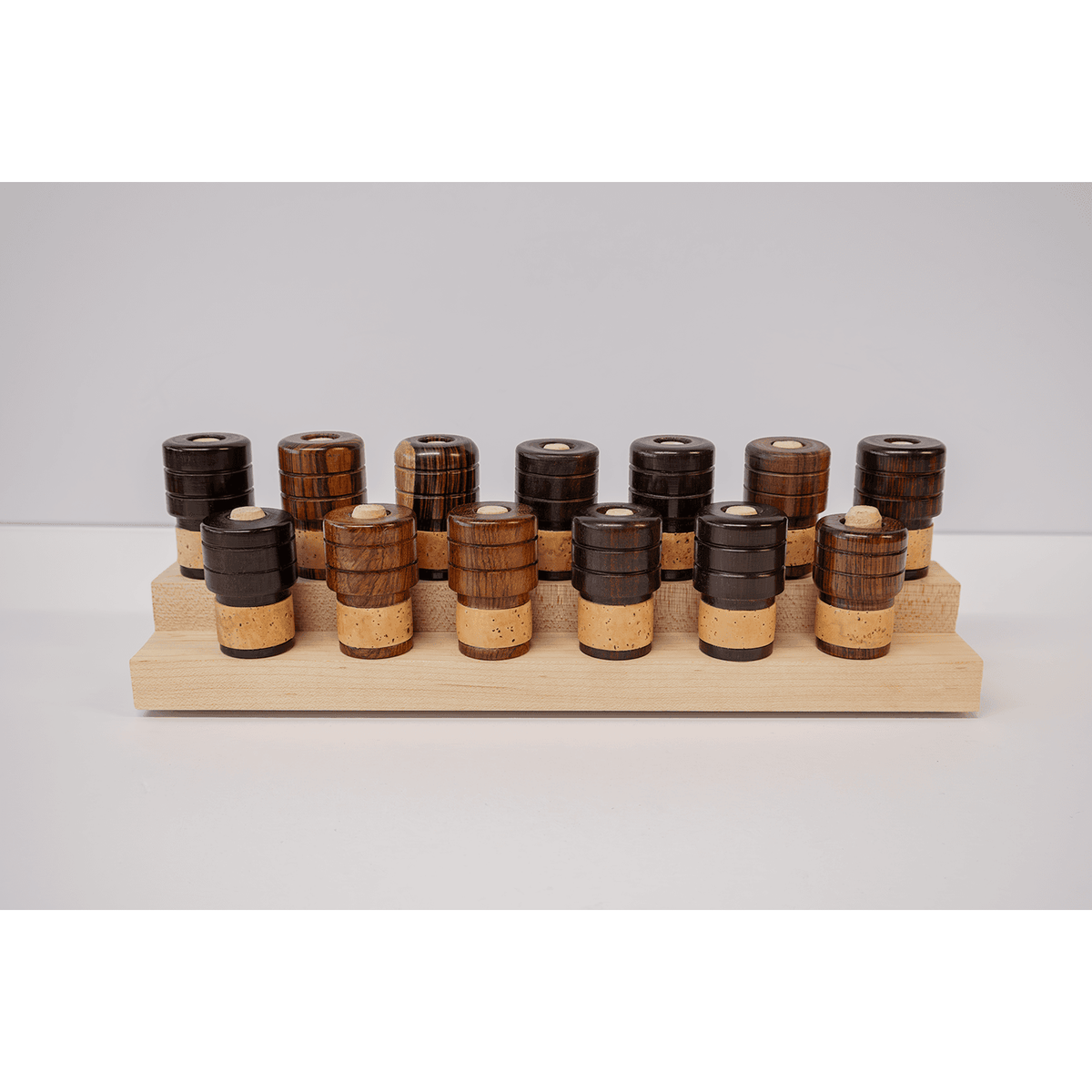 Various wooden tenor saxophone end plugs arranged on a two their peg stand - 7 upper row and 6 bottom row
