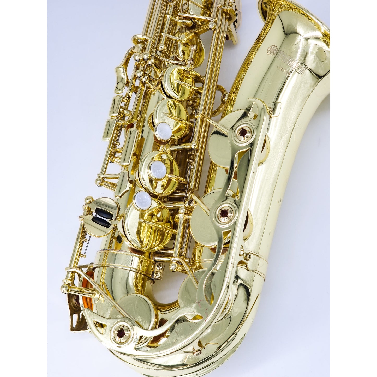 Gold saxophone on a white background, closeup on lower stack (right hand) keys and bell