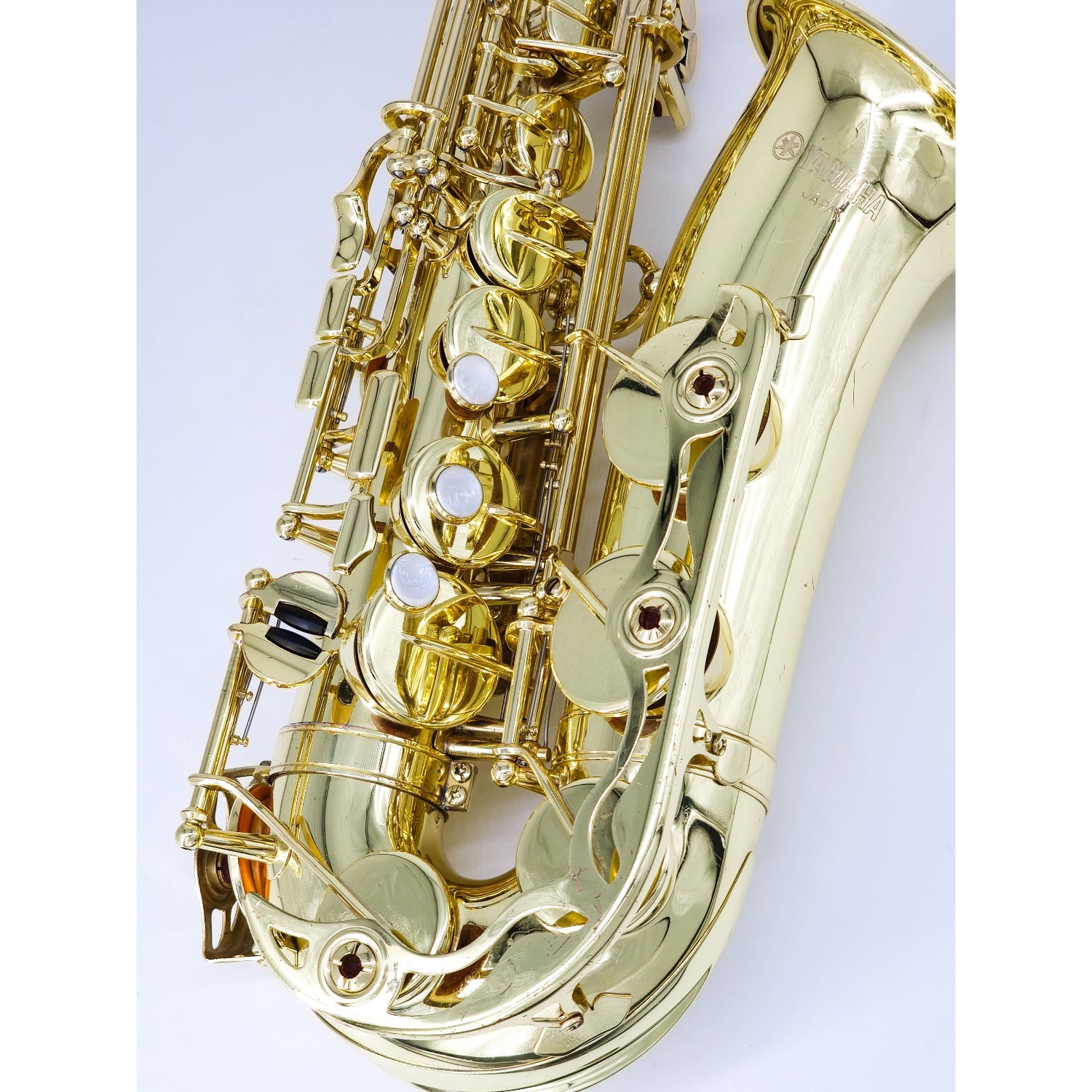 Gold saxophone on a white background, closeup on lower stack (right hand) keys and bell