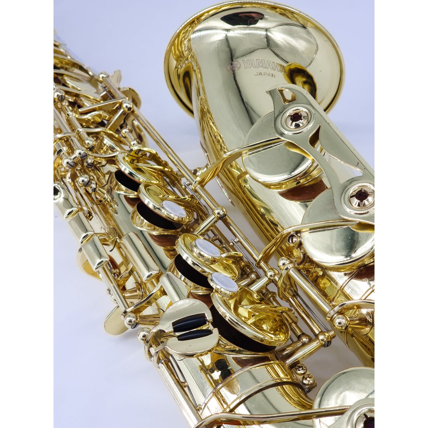Close-up of a gold saxophone on a white background, showing high F# key