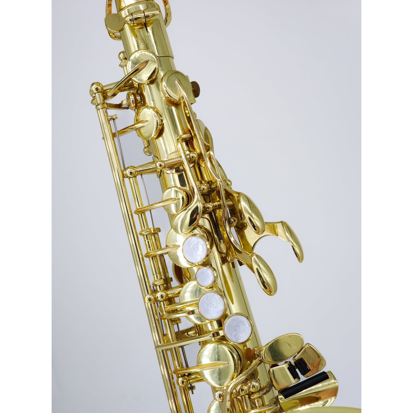 Gold saxophone on a light gray background, closeup of left hand (upper stack) keys 