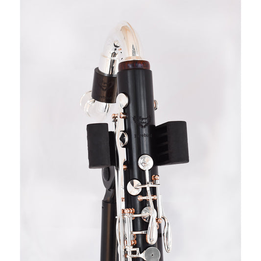 Upper half of top joint with neck attached, resting in a bass clarinet stand, showing detail of Royal Global Firebird logo and the rose gold plating of the posts contrasting with the silver keys